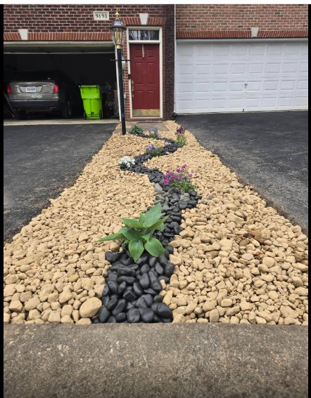 After Wonder Yard landscaping work, river rock bed with black accent stones and flowers